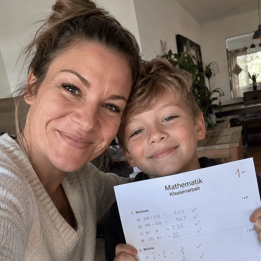 Mutter und Sohn halten eine Klassenarbeit mit der Note 1 minus in die Kamera